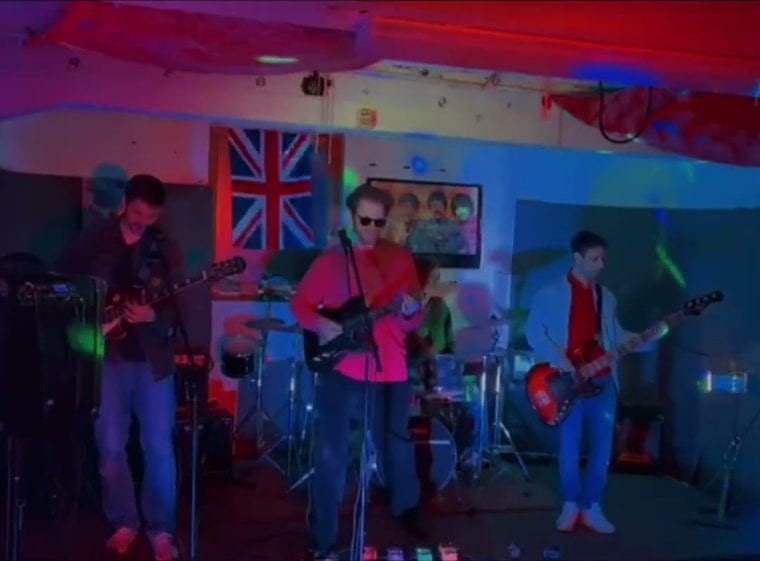 Die komplette Band auf der Proberaum-Bühne, rotes und blaues Licht
